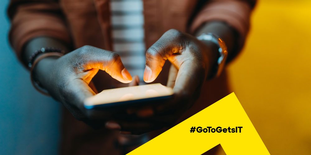 Close up image of man holding a smartphone in a darkened space, representing potential BYOD nightmares IT teams face when supporting remote and flexible work