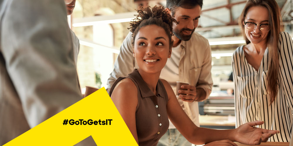 Coworkers gathering around a desk as a woman presents differences between on prem vs cloud security