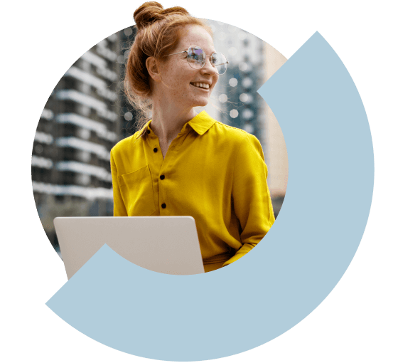 Una donna che sorride mentre lavora sul suo laptop all'aperto.